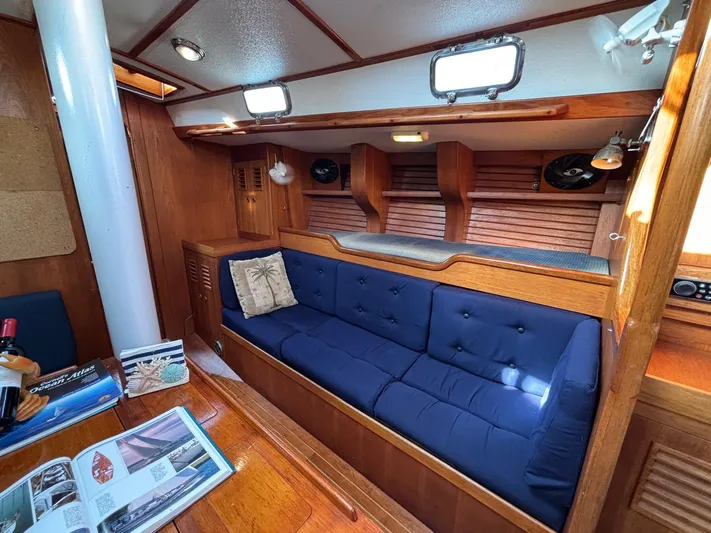 Colleen Yacht Photos Pics Cozy 1984 Cambria 44/46 yacht interior with blue cushioned seating and wooden accents.