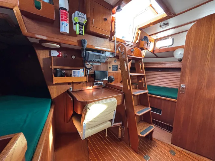 Colleen Yacht Photos Pics 1984 Cambria 44/46 yacht interior with wooden finish, navigation equipment, and cozy seating.