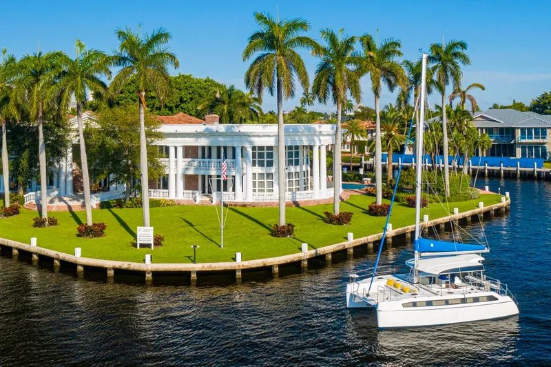  Yacht Photos Pics Luxurious waterfront mansion with palm trees and a Smart Cat S280 catamaran docked nearby.