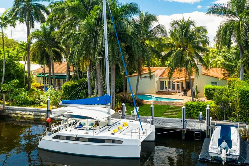  Yacht Photos Pics Catamaran docked by tropical villa, surrounded by palm trees, featuring a Smart Cat S280, 2025 model.