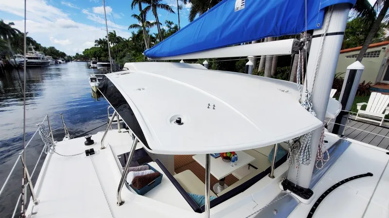  Yacht Photos Pics Modern Smart Cat S280 sailboat docked by a scenic waterway, featuring a sleek design and blue sail.