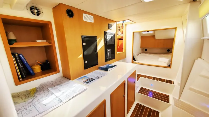  Yacht Photos Pics Modern Smart Cat S280 yacht interior with navigation maps, wooden cabinetry, and cozy sleeping area, 2025 model.