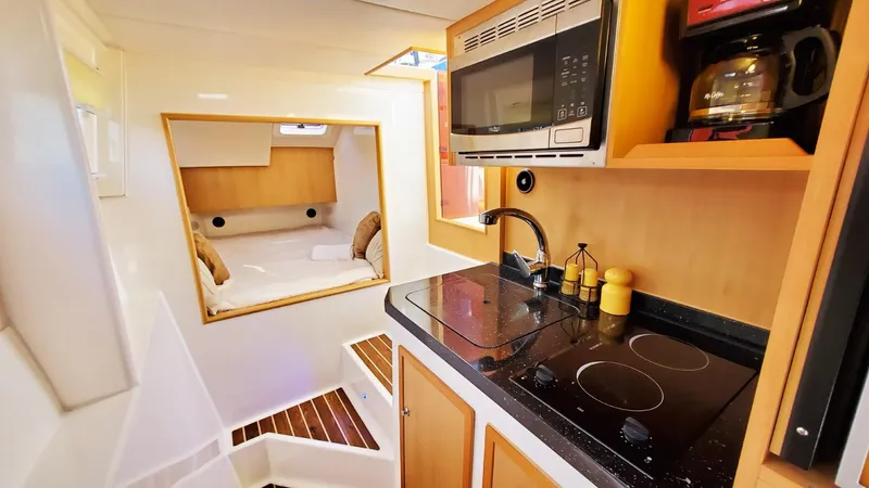  Yacht Photos Pics Modern kitchen interior in 2025 Smart Cat S280 yacht, featuring stove, microwave, and cozy cabin.
