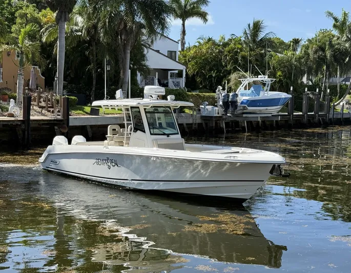  Yacht Photos Pics 2020 Boston Whaler 330 Outrage boat docked near palm trees and waterfront homes.