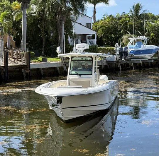  Yacht Photos Pics 2020 Boston Whaler 330 Outrage boat cruising on a calm waterway, surrounded by lush greenery.