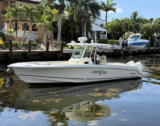  Yacht Photos Pics 2020 Boston Whaler 330 Outrage boat docked by tropical waterfront homes.