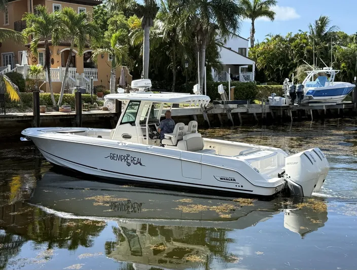  Yacht Photos Pics 2020 Boston Whaler 330 Outrage boat docked near waterfront homes, surrounded by palm trees.