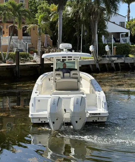  Yacht Photos Pics 2020 Boston Whaler 330 Outrage boat navigating a canal with palm trees in the background.