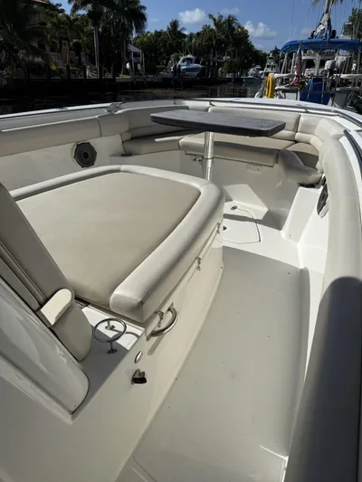 Yacht Photos Pics 2020 Boston Whaler 330 Outrage boat interior with seating and table, docked near palm trees.