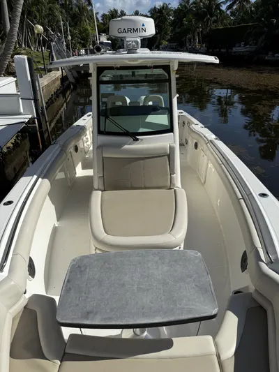  Yacht Photos Pics 2020 Boston Whaler 330 Outrage boat interior with seating and table, docked by palm trees.