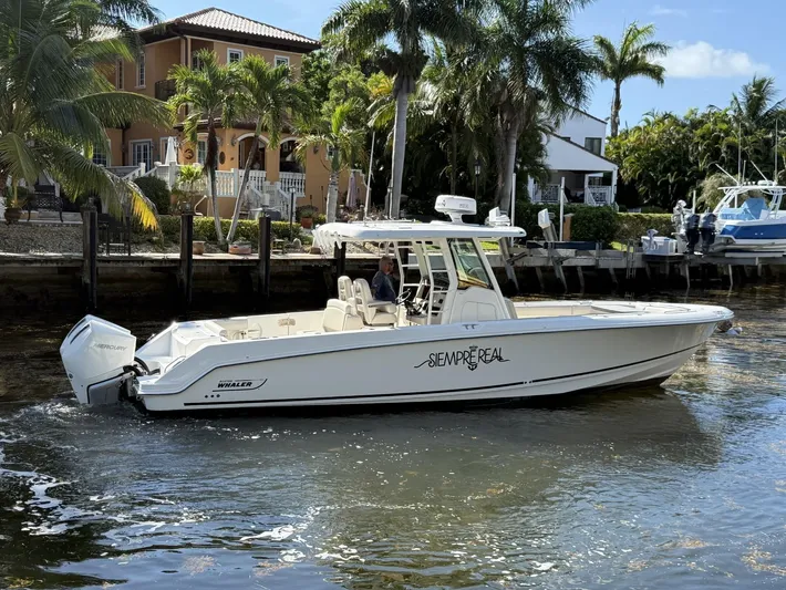  Yacht Photos Pics 2020 Boston Whaler 330 Outrage boat cruising near waterfront homes with palm trees.