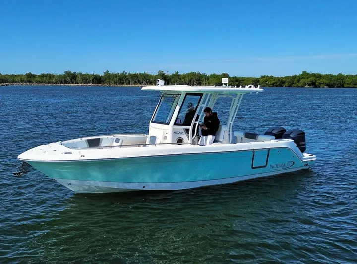  Yacht Photos Pics 2021 Robalo 272 boat on calm water, clear sky, side view.