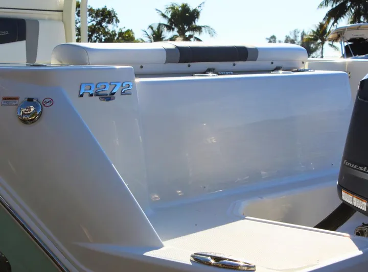  Yacht Photos Pics 2021 Robalo 272 boat stern with sleek design and logo, surrounded by tropical scenery.