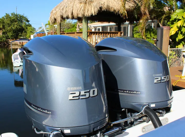  Yacht Photos Pics 2021 Robalo 272 boat with twin Yamaha 250 outboard engines, docked near tropical foliage.