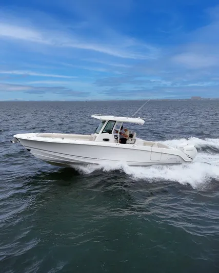  Yacht Photos Pics 2021 Boston Whaler 330 Outrage cruising on open water under a clear blue sky.
