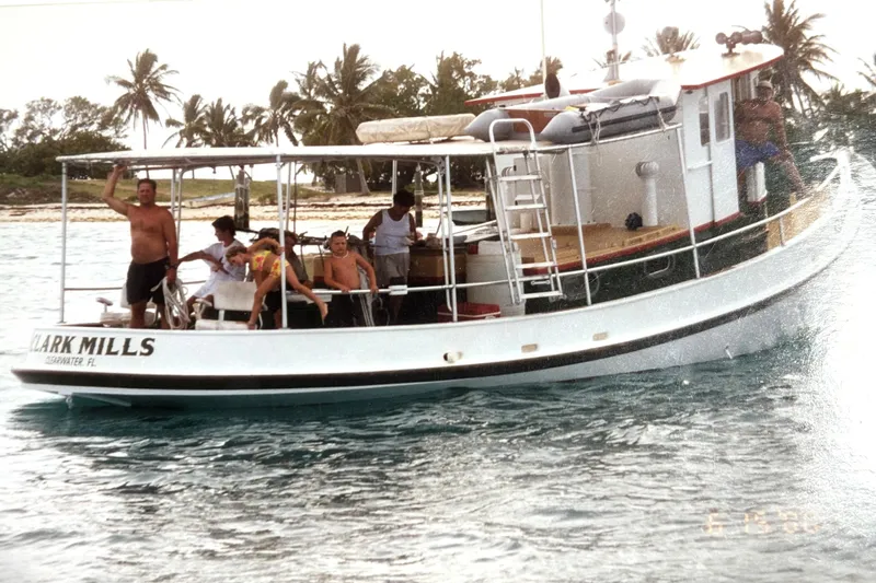 Clark Mills Yacht Photos Pics Custom 1972 tug boat with people onboard, near tropical island and palm trees.