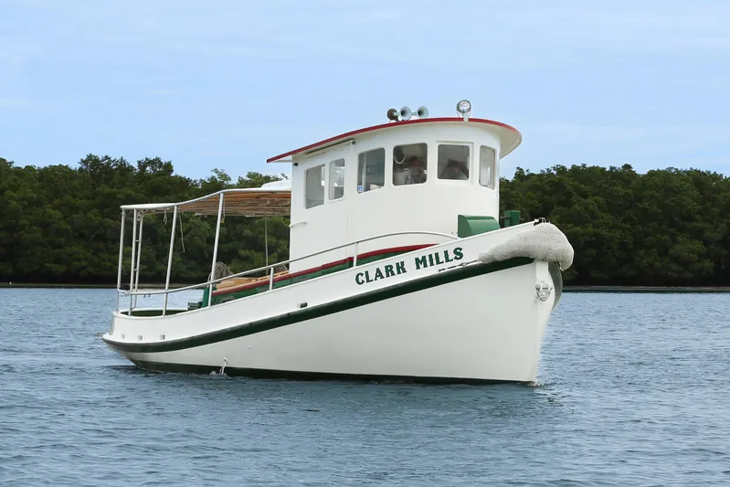 Clark Mills Yacht Photos Pics 1972 Mills Boat Works Tug Boat on calm water, surrounded by lush greenery.