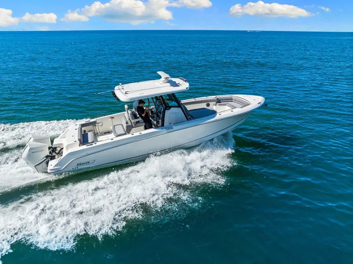  Yacht Photos Pics 2022 Boston Whaler 330 Outrage cruising on open blue ocean under clear skies.