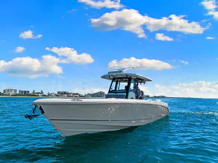  Yacht Photos Pics 2022 Boston Whaler 330 Outrage boat cruising on clear blue water under a sunny sky.