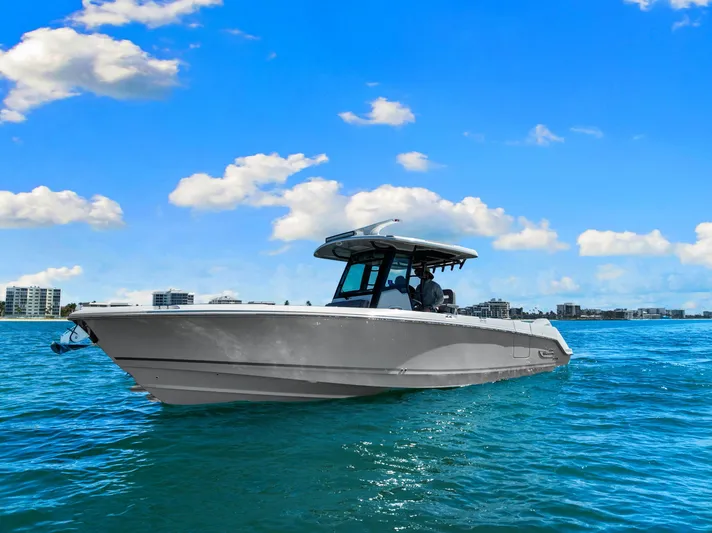  Yacht Photos Pics 2022 Boston Whaler 330 Outrage boat cruising on clear blue water under a sunny sky.