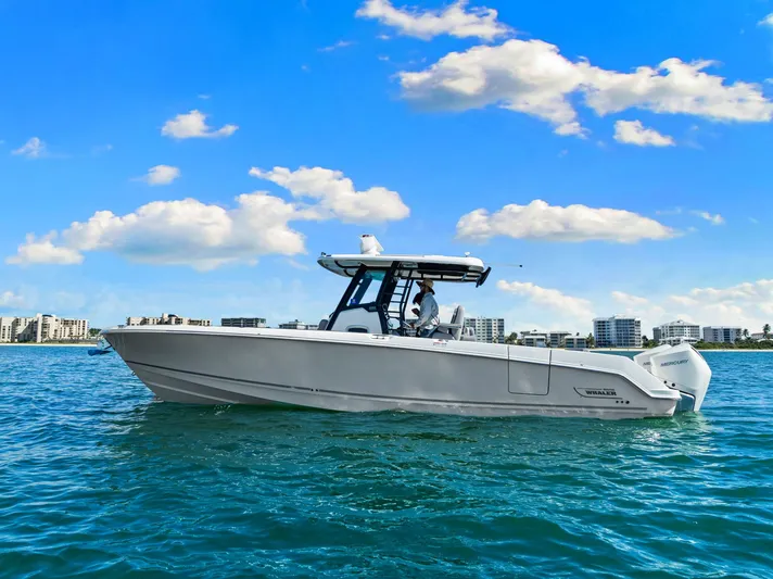  Yacht Photos Pics 2022 Boston Whaler 330 Outrage boat cruising on clear blue water under a sunny sky.