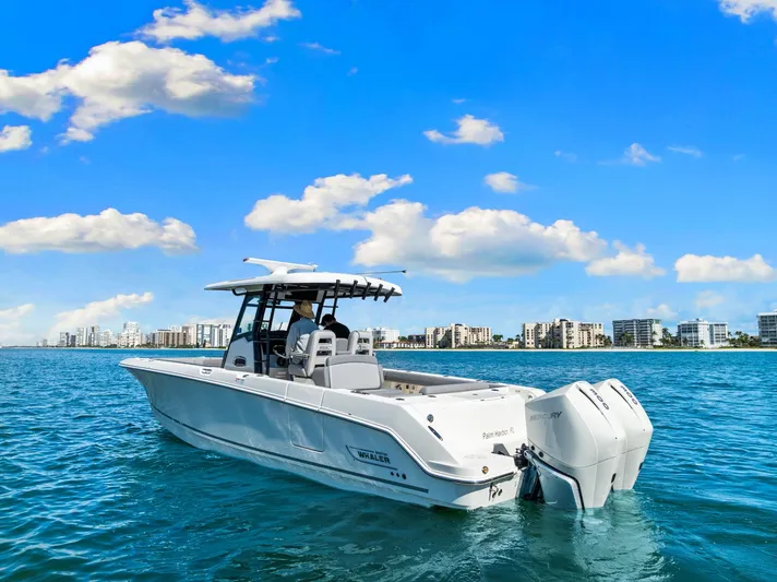  Yacht Photos Pics 2022 Boston Whaler 330 Outrage boat on blue water with city skyline background.