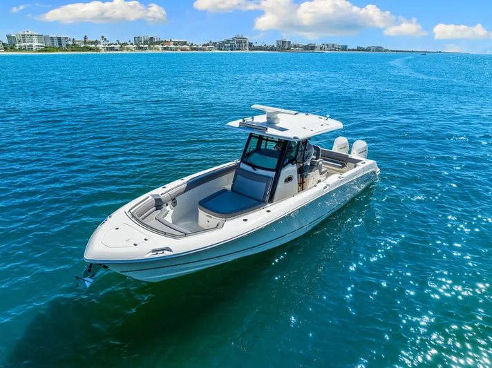  Yacht Photos Pics 2022 Boston Whaler 330 Outrage boat on clear blue ocean near coastline.