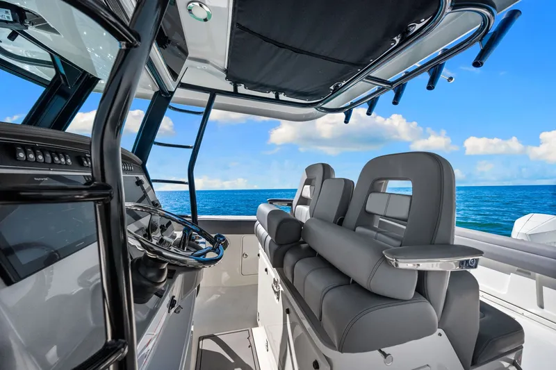  Yacht Photos Pics 2022 Boston Whaler 330 Outrage interior with ocean view, featuring sleek seating and modern controls.