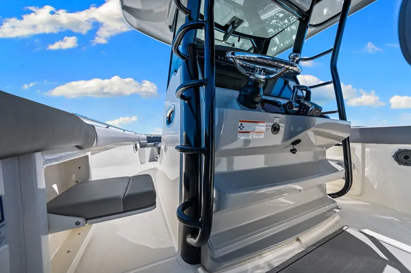  Yacht Photos Pics 2022 Boston Whaler 330 Outrage helm with modern controls and seating under a clear blue sky.