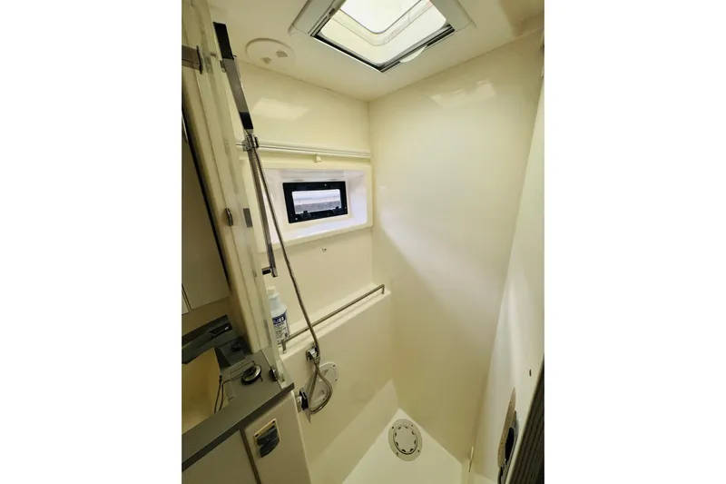 Stargazer Yacht Photos Pics Compact shower area in a 2017 Robertson and Caine Leopard yacht, featuring a skylight and window.