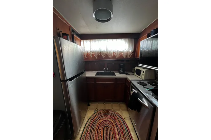  Yacht Photos Pics 1978 Hatteras 53 Yacht Fisherman kitchen with appliances, wooden cabinets, and a colorful rug.