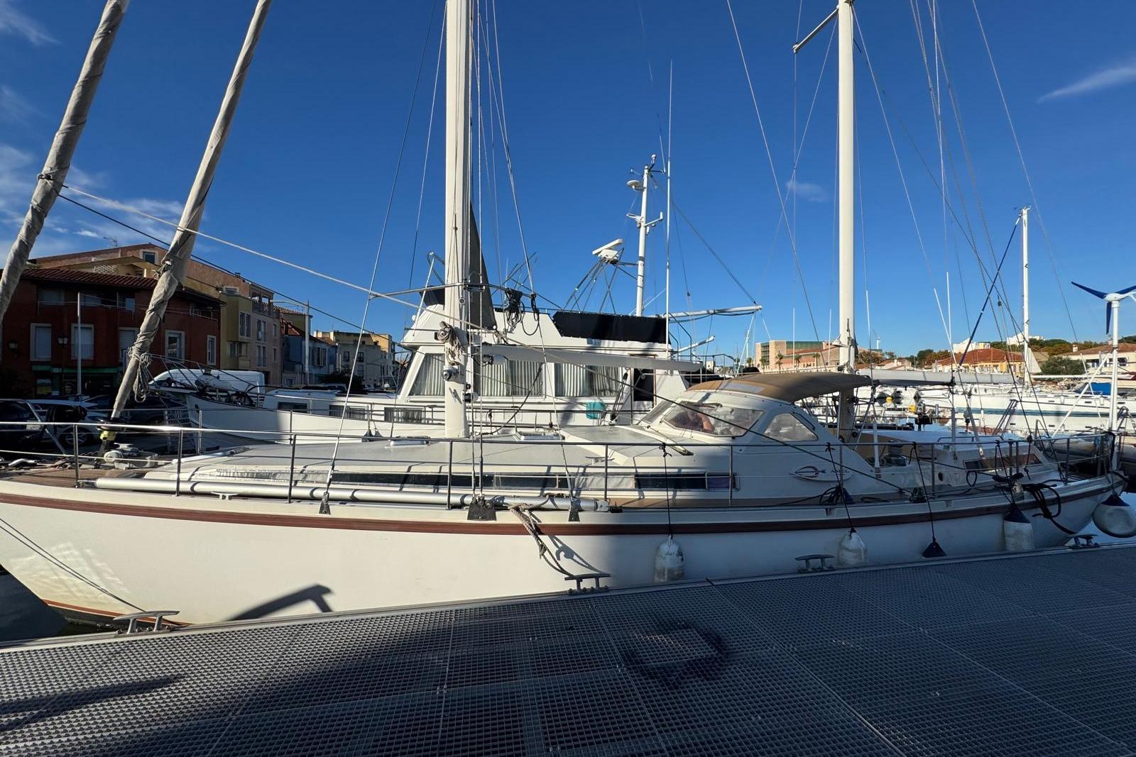 Sailboat Amel Super Maramu 2000, 2002 model, docked at a marina under clear blue skies.
