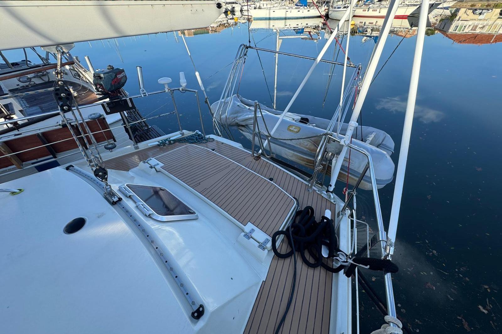 Deck view of 2002 Amel Super Maramu 2000 yacht with dinghy and calm water reflection.