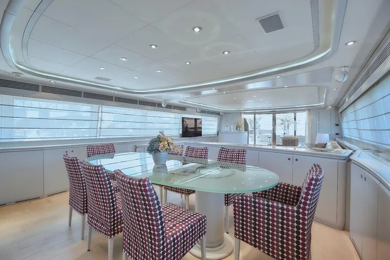 Camarik Yacht Photos Pics Luxurious yacht interior with modern dining area, glass table, patterned chairs, and large windows. Custom Line 112, 2005.