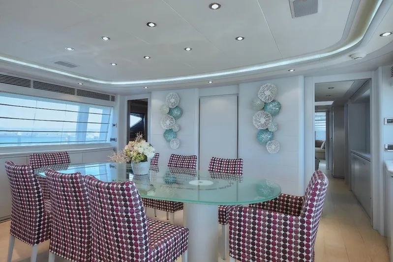 Camarik Yacht Photos Pics Luxurious yacht interior with modern dining area, glass table, patterned chairs, and elegant decor.