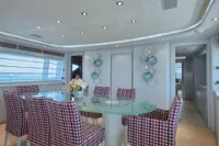 Luxurious yacht interior with modern dining area, glass table, patterned chairs, and elegant decor.