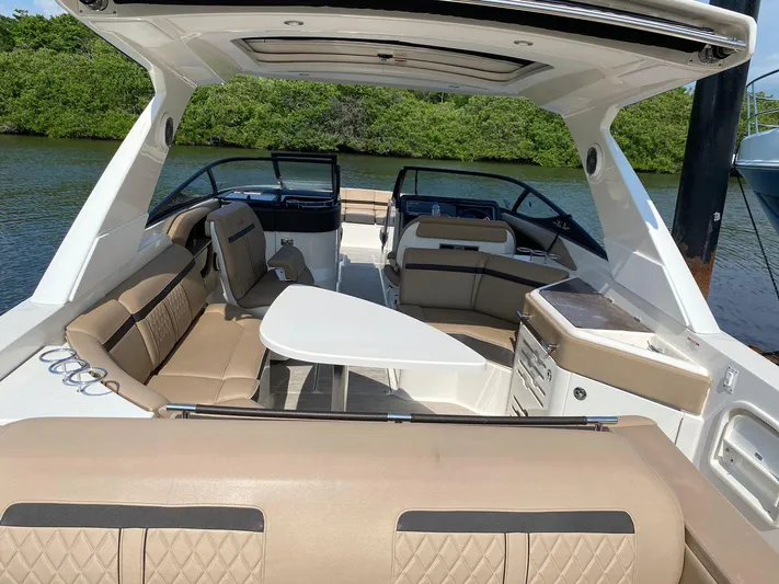 2017 Sea Ray 310 Slx @ Puerto Vallarta Yacht Photos Pics 2017 Sea Ray 310 SLX boat interior with beige seating and table, docked by lush greenery.