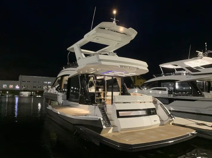  Yacht Photos Pics 2024 Galeon 500 Fly yacht illuminated at night in a marina setting.