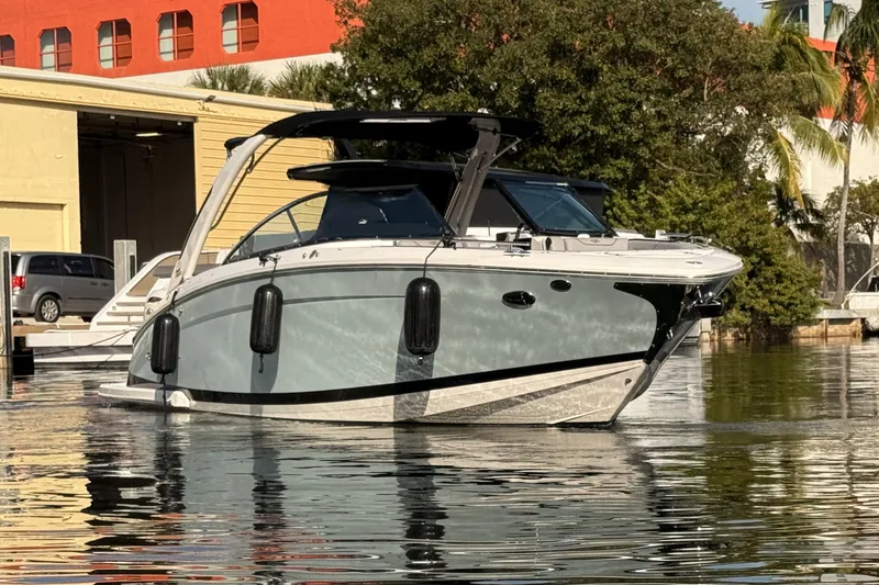  Yacht Photos Pics 2024 Regal LX9 boat docked on calm water, surrounded by trees and buildings.