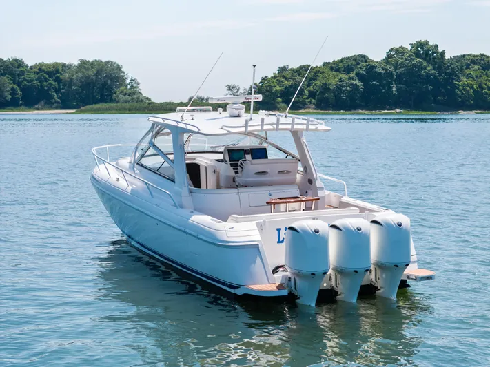 Lil' Sumpin II Yacht Photos Pics 2015 Intrepid 430 Sport Yacht on serene water with lush green shoreline.