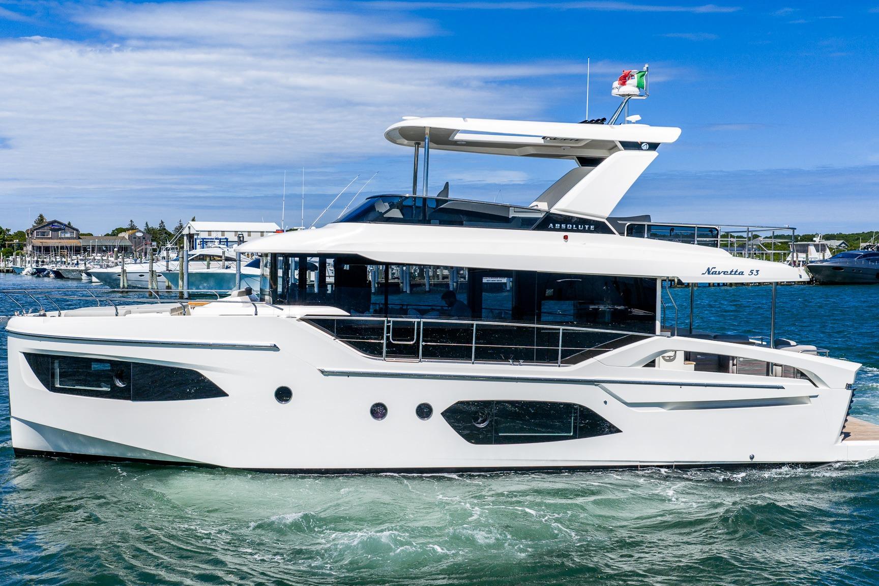 2026 Absolute Navetta 53 yacht cruising in a marina under a clear blue sky.