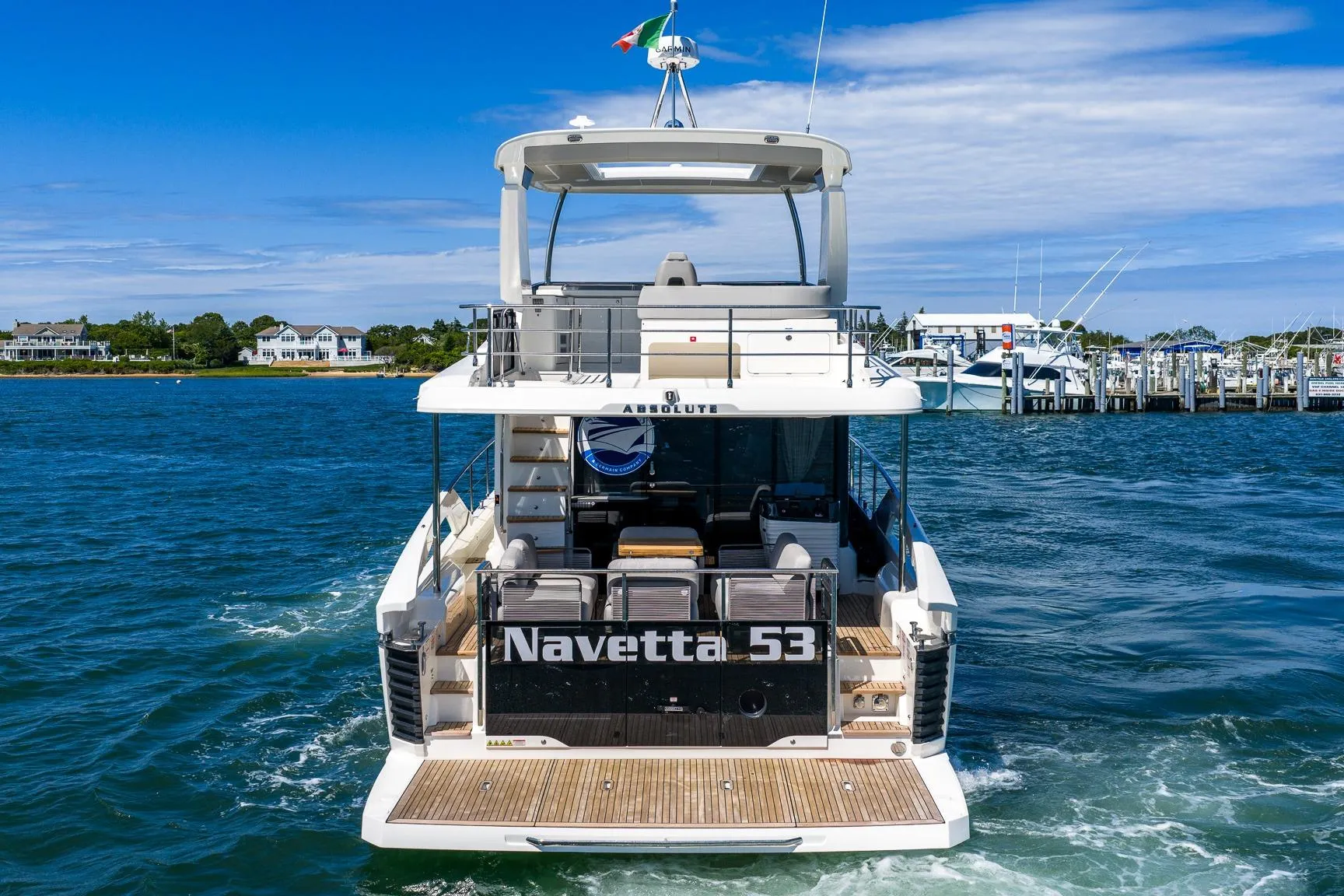 Rear view of 2026 Absolute Navetta 53 yacht cruising in a scenic marina.