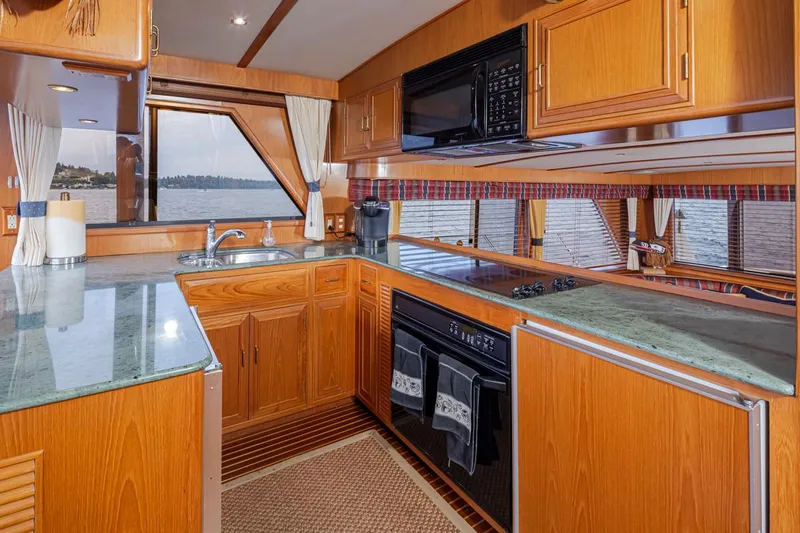 Black Ice Yacht Photos Pics 1998 Ocean Alexander 64 yacht kitchen with wood cabinetry and ocean view.