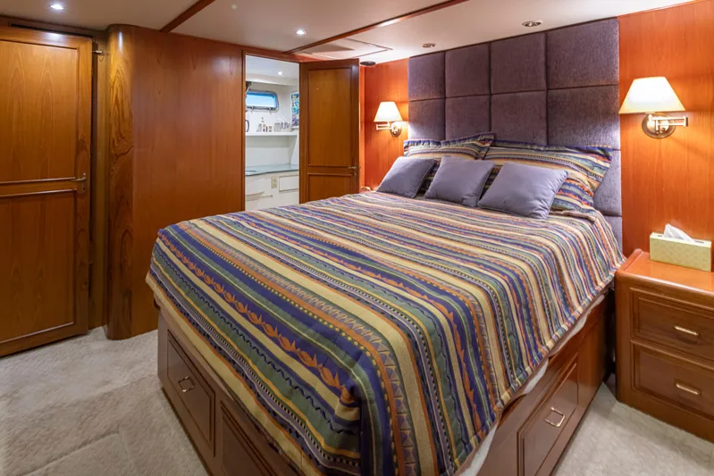 Black Ice Yacht Photos Pics Luxurious bedroom in a 1998 Ocean Alexander 64 yacht with wood paneling and cozy lighting.