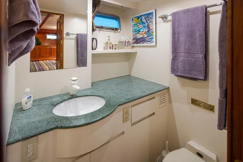 Black Ice Yacht Photos Pics Bathroom interior of a 1998 Ocean Alexander 64 yacht with green countertop and purple towels.