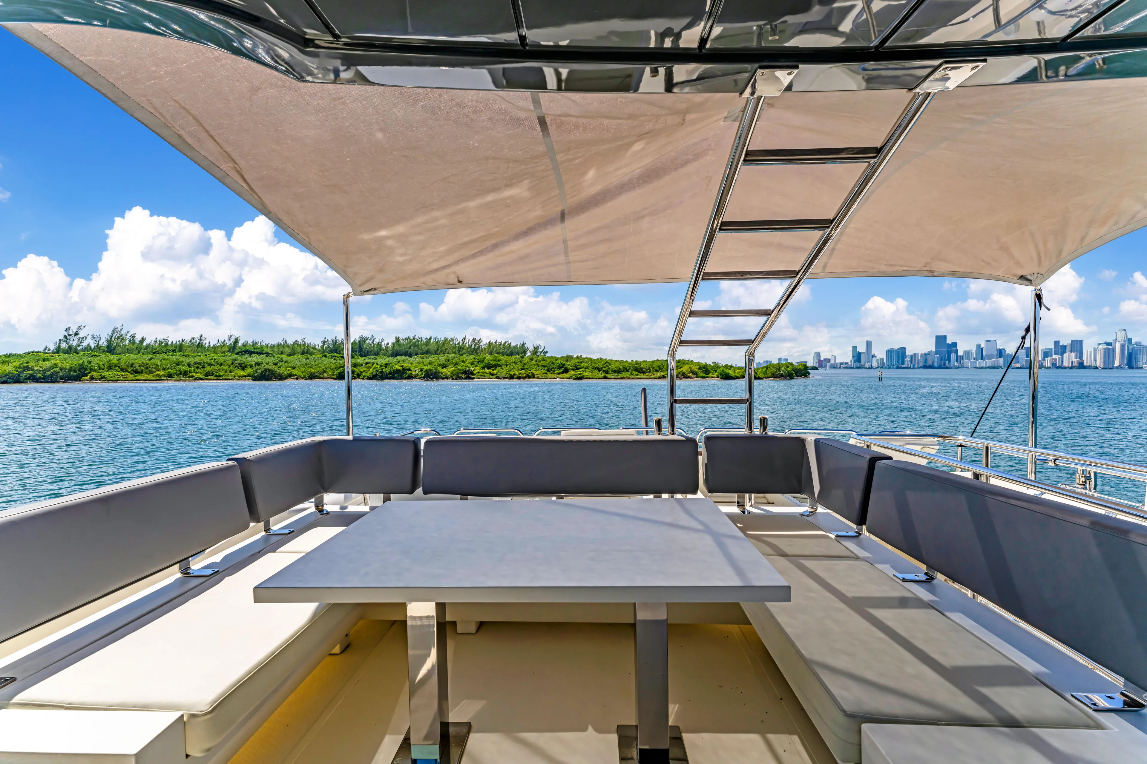 Seaduction Yacht Photos Pics Astondoa 80 GLX 2016 yacht deck with seating, table, and canopy, overlooking scenic water view.