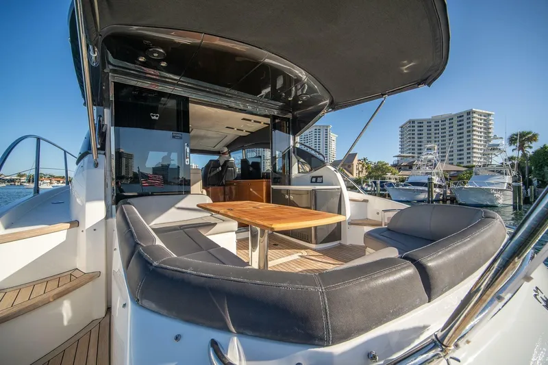 Sea-licious Yacht Photos Pics 2016 Princess V48 yacht with luxurious seating and table, docked near waterfront buildings.
