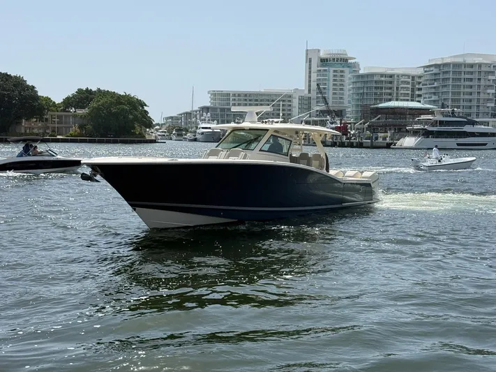 Reel Patience Yacht Photos Pics 2019 Scout 420 LXF boat cruising in a marina with modern buildings in the background.
