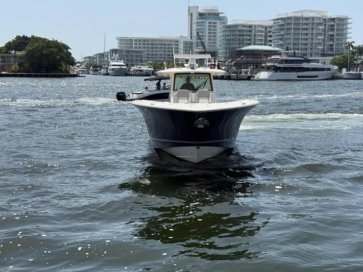 Reel Patience Yacht Photos Pics 2019 Scout 420 LXF boat cruising in a marina with modern buildings in the background.