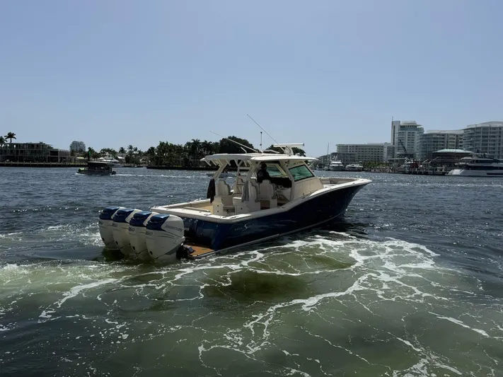 Reel Patience Yacht Photos Pics 2019 Scout 420 LXF boat cruising in a marina with modern buildings in the background.